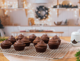 Chocolate cupcakes on wire cooling rack in kitchen decorated for Christmas
