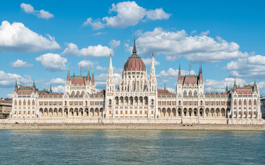 Fototapeta na wymiar Hungarian Parliament building in Budapest, Hungary. View across Danube River, with summer clouds.