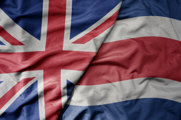 big waving national colorful flag of great britain and national flag of costa rica .