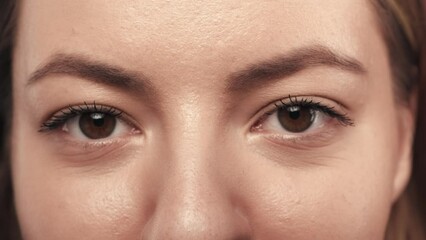 Orchid flowers cover woman's eyes close up. The woman removes the flowers and looks straight ahead. Good vision and eye care. Contact lenses. Natural female beauty. Slow motion.