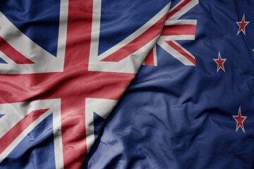 big waving national colorful flag of great britain and national flag of new zealand .