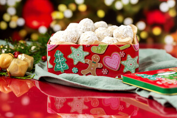 Pecan Sandies in Christmas Tin on Red Countertop with Christmas Tree in Background