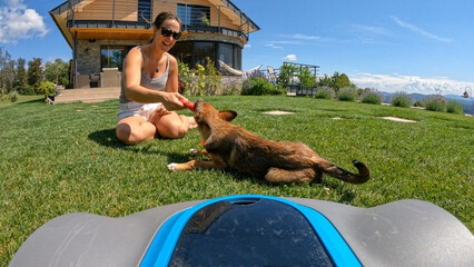 POV = POINT OF VIEW: Carefree play of a lady and her dog while robot mows grass