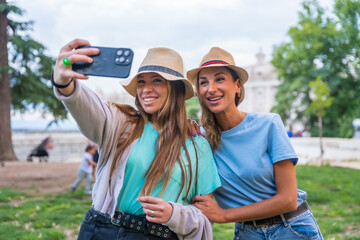 Two female friends in the city smiling and having fun making a selfie with the phone
