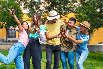 Multi ethnic group of friends partying in a city park having fun with bottles of beers