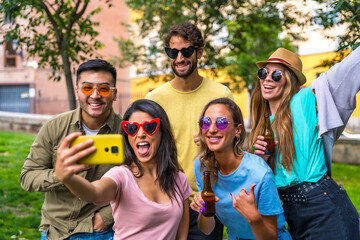 Obraz premium Multi ethnic group of friends partying in the city park taking a selfie, friendship and fun concept with sunglasses