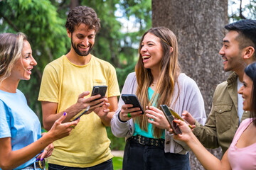 Multiethnic group smiling with phones on internet or social networks in the park, technology concept