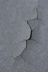 Peeling paint on the wall. Old concrete wall with cracked flaking paint. Weathered rough painted surface with patterns of cracks and peeling. Grunge texture for background and design. High resolution.