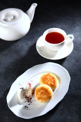 Cottage cheese pancakes, cheesecakes, ricotta pancakes with sour cream on dark background.Healthy and delicious breakfast. Top view, place to copy