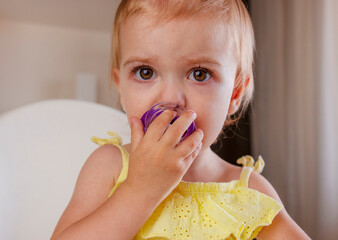 Toddler girl with pacifier sitting on highchair