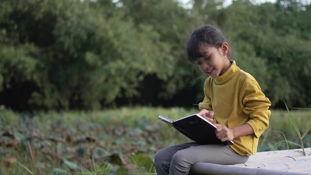 A Little girl reading a diary in the park.