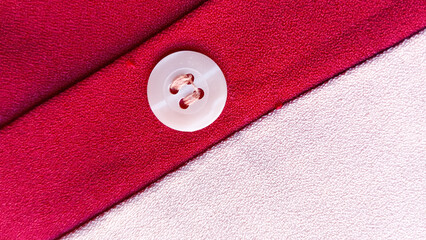 Red and dusty pink clothing fabric texture. A button on the cloth.

