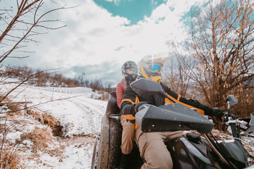 A young adventurous couple embraces the joy of love and thrill as they ride an ATV Quad through the snowy mountainous terrain © Minet