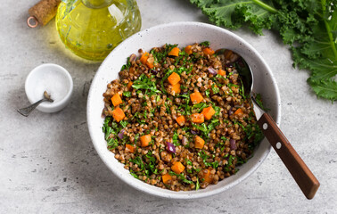 Buckwheat with vegetables and kale on a gray textured background, top view. Delicious healthy vegan food