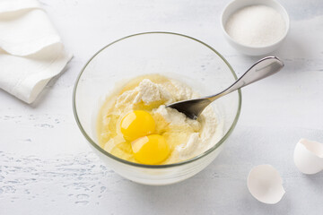 Glass bowl with soaked semolina, eggs and a bowl of sugar. cooking mannik, cake or pie on a light blue background. step by step, cooking step - 628298682