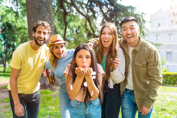 Portrait multiethnic group partying throwing confetti in the park, fun with friends concept