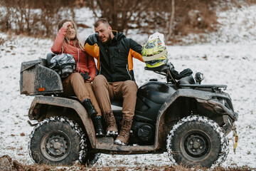 Fototapeta na wymiar A young adventurous couple embraces the joy of love and thrill as they ride an ATV Quad through the snowy mountainous terrain