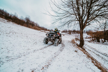 A young adventurous couple embraces the joy of love and thrill as they ride an ATV Quad through the snowy mountainous terrain