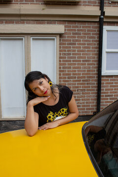 CHICA DE NEGRO CON GIRASOLES SOBRE COFRE DE TAXI AMARILLO