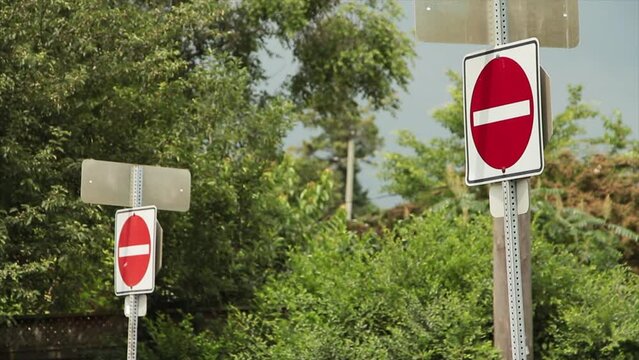 two do not enter road street signs, one in foreground and the other in background, red circle with white line in it on white background, close shot