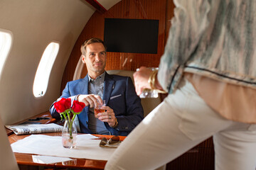 Successful couple having cocktail before takeoff aboard a private jet airplane