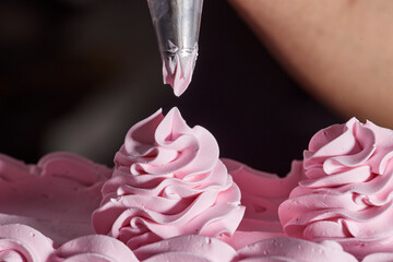 Detail strawberry icing flower accents on chocolate layer cake, piping tip on edge of frame 