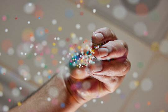 Low angle view of decorative sprinkles falling from bakers hand 