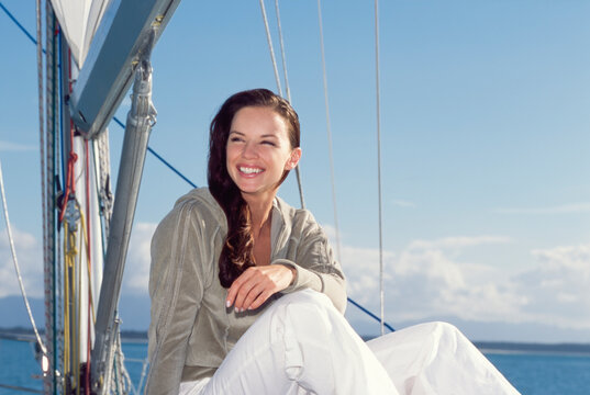  Young woman sitting next to sail and boom smiling on yacht 