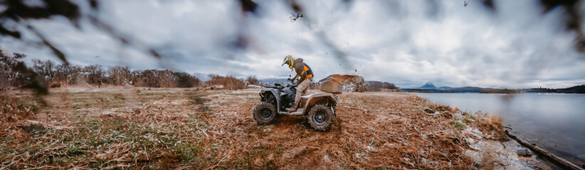Fototapeta na wymiar Wide photo of a man is fearlessly enjoying an adventurous ride on an ATV Quad through hazardous snowy terrain, embracing the thrill and excitement of the challenging mountainous landscape