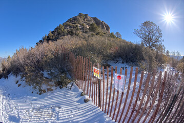 View of Thumb Butte summit from the hiking trail in the Prescott National Forest, covered in winter snow and ice. Summit is fenced off to protect Peregrine Falcon nesting habitat.