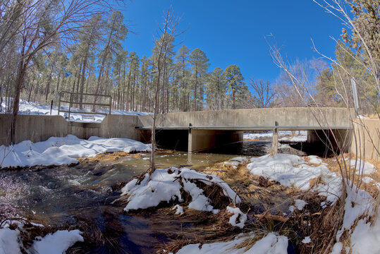 Miller Creek flowing under a bridge at the Thumb Butte Recreation Area in the Prescott National Forest just west of Prescott Arizona, covered in winter snow and ice. - Powered by Adobe