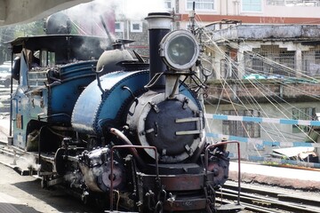 Iconic blue Darjeeling Himalayan Railway locomotive arriving at Darjeeling station, evoking the nostalgia of a bygone era.