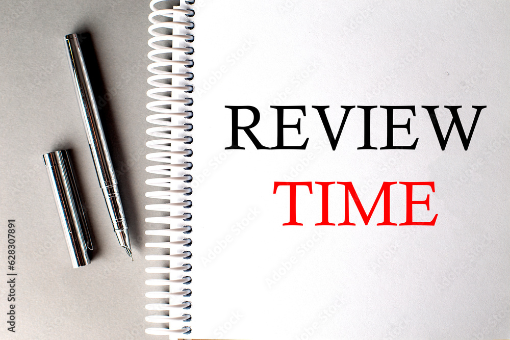 Poster review time text on a notebook with pen on grey background