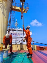 Crews or seaman are lubricating or greasing Hoisting wire of deck crane during renewal operation.