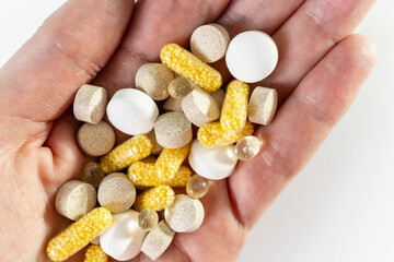 Different pills vitamins on the  hand on white table.  Medical, vitamins, health background