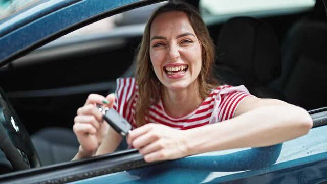 Young blonde woman smiling confident holding key of new car at street