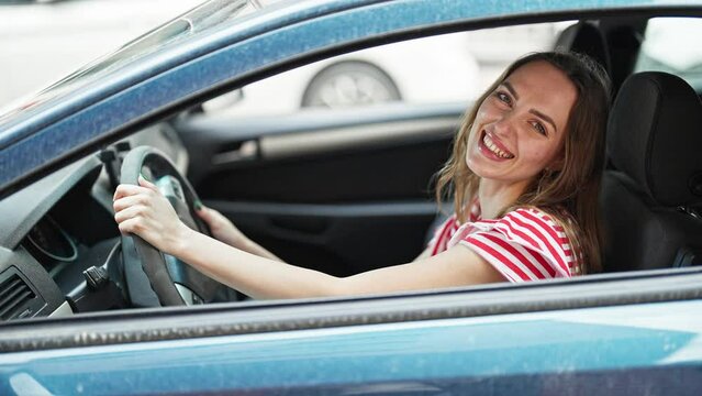 Young blonde woman driving a car smiling at street