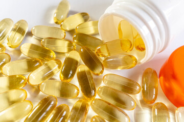 Close up yellow capsules and a bottle on the white background. Omega 3 oil in capsules. Medical, vitamins, health background