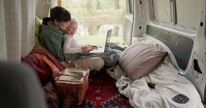 Mom, girl and camping vacation with laptop, van or transport for typing, search or games by lake. Computer, mother and daughter with click, keyboard or bonding in camper with video, movie or learning