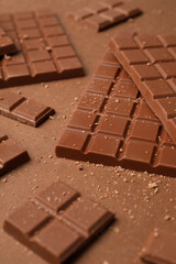 Pieces of tasty chocolate on brown background