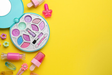 Eye shadow palette and other decorative cosmetics for kids on yellow background, flat lay. Space for text
