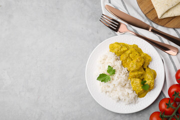 Delicious rice, chicken with curry sauce and tomatoes on light grey table, flat lay. Space for text