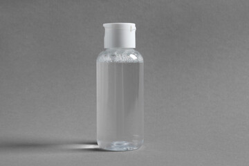 Transparent bottle with cosmetic product on grey background