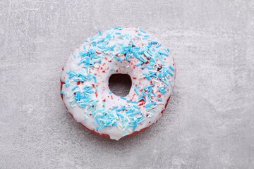 Obraz na płótnie Canvas Sweet glazed donut decorated with sprinkles on light grey table, top view. Tasty confectionery