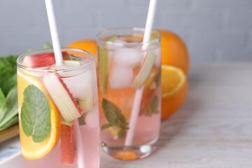 Tasty rhubarb cocktail with orange on white wooden table, closeup. Space for text