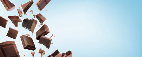 Broken chocolate bar pieces falling on light blue background. Banner design with space for text