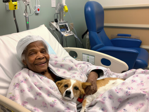 Sick elderly black woman lying in a hospital bed with a therapy dog on her lap. She is smiling at the camera.
