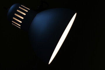 desk lamp close up against dark background as a contrast silhouette shining down and screen right