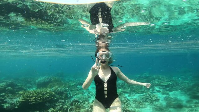 Scuba diver, peace sign and woman swimming in ocean for adventure, holiday and vacation in Mauritius. Snorkeling, travel and female person in tropical water with hand gesture to explore on island