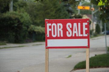 generic for sale sign on front lawn of residential home in white writing on red background and wood...
